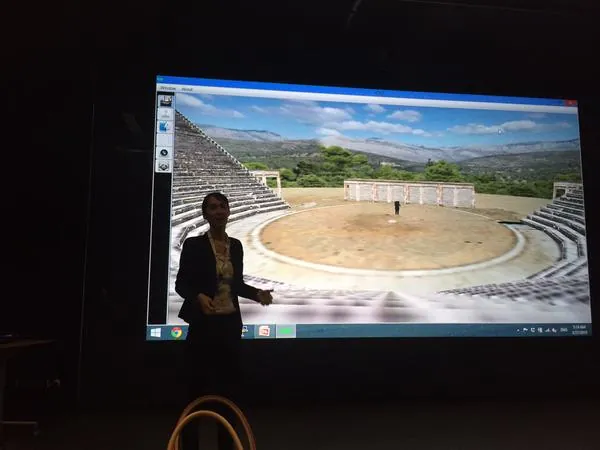 A speaker presenting a 3D visualization of an ancient theatre on a large screen.