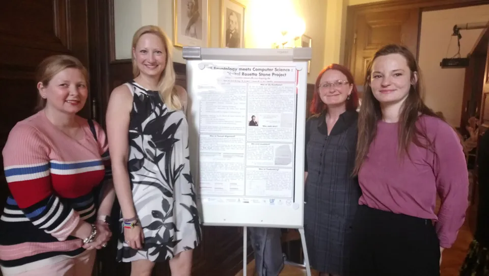 Four women standing beside a research poster at a conference.